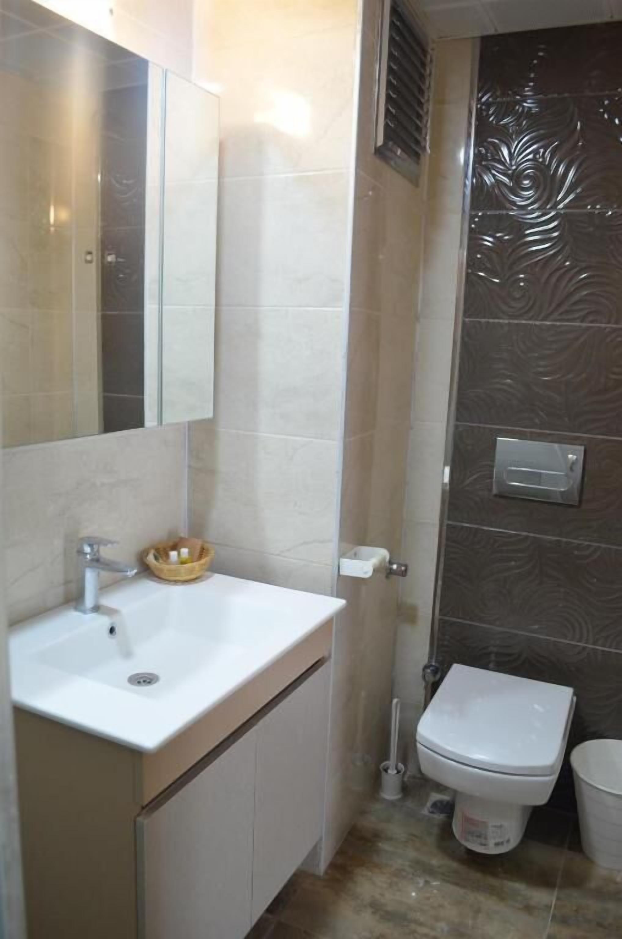 A bathroom with a white sink, mirror, and toilet.