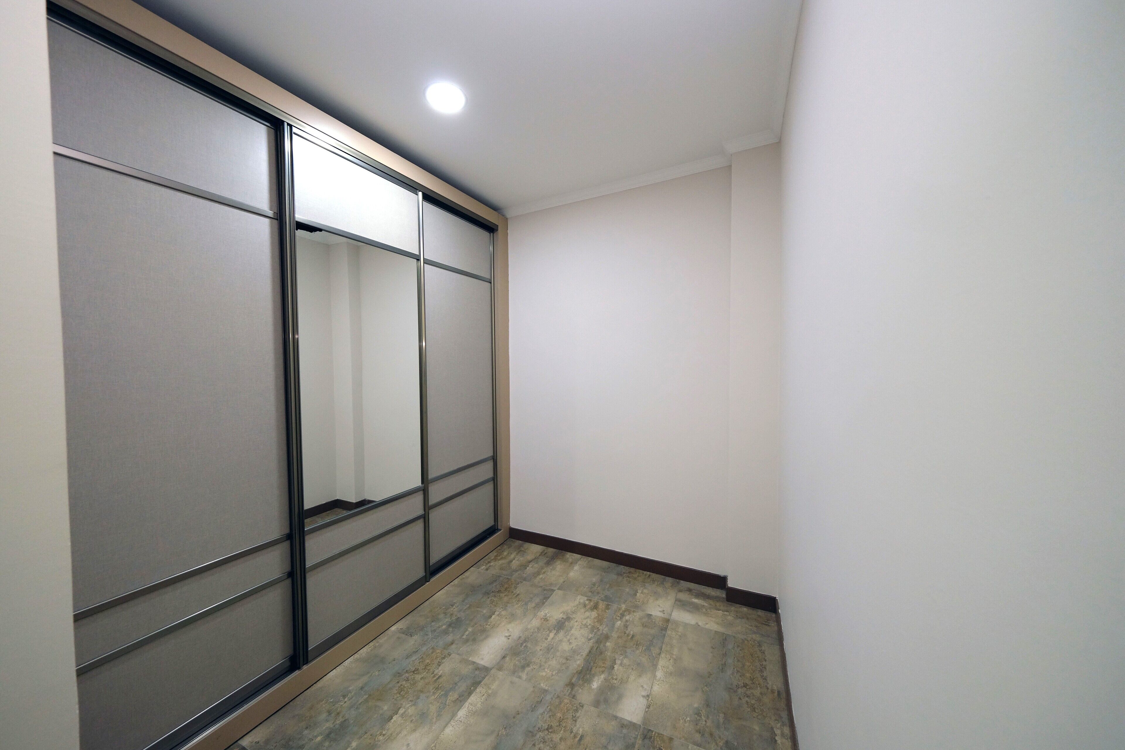 A narrow hallway with a sliding door closet, a tiled floor, and a ceiling light.
