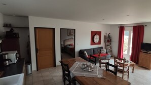 Un salon moderne comprenant un coin repas, un canapé, un téléviseur et un rideau rouge.