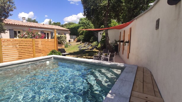 Une piscine dotée d’une terrasse en bois et d’un auvent rouge.