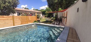 Une piscine dotée d’une terrasse en bois et d’un auvent rouge.