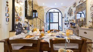 Un comedor con pared de piedra, una escalera y vistas a través de un amplio ventanal.
