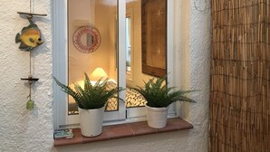 Ein Fenster mit zwei Blumentöpfen, einem Wandbild mit Fischen und einem runden Spiegel.