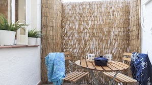 Eine Terrass mit einem Bambus Sichtschutz, einem runden Holztisch und zwei Stühlen.