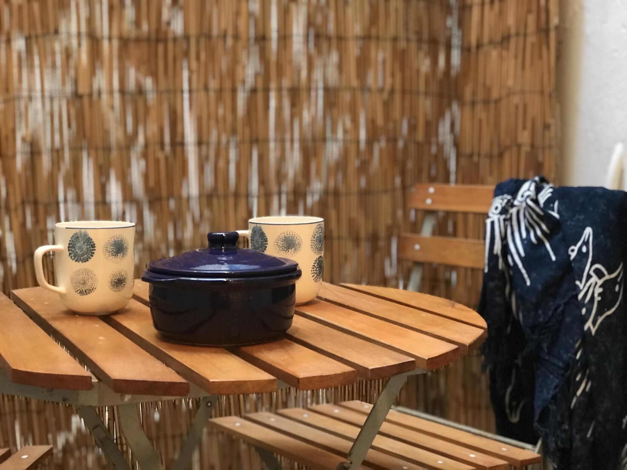 A table with a ceramic pot and two patterned cups.