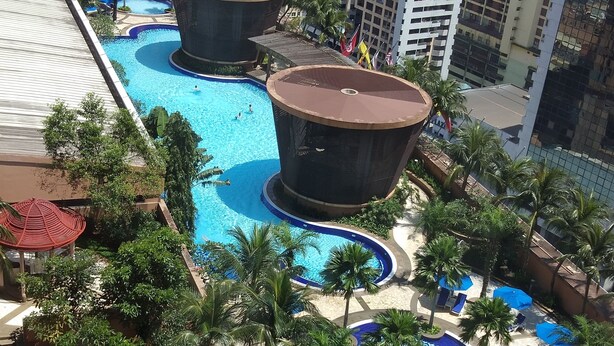 A rooftop pool area with multiple swimming pools, palm trees, and a large building labeled "MENARA" in the background. - Times Square Residence At Kuala Lumpur (Kuala Lumpur)