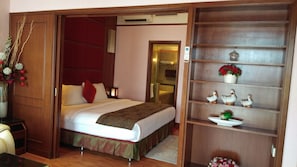 A hotel room with a bed, a nightstand, a shelf with decorative items, and a mirror. - Times Square Residence At Kuala Lumpur (Kuala Lumpur)