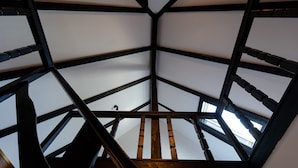 Eine hohe Decke mit Holzbalken und einer zentralen Holztreppe.