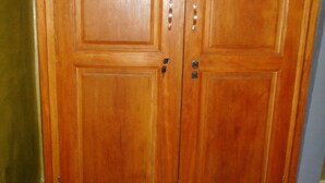 A large wooden wardrobe with two doors and a drawer, featuring metal handles and a keyhole. - Kimis Place (Douala)
