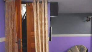 A room with a bed, a chair, a television, and a curtain. - Kimis Place (Douala)