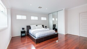 Une chambre moderne avec un grand lit, une table de chevet, un miroir et une porte coulissante.