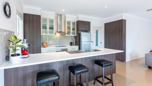 Une cuisine moderne dotée d’un grand îlot central, de meubles en bois foncé, d’appareils électroménagers en acier inoxydable et d’une plante en pot.