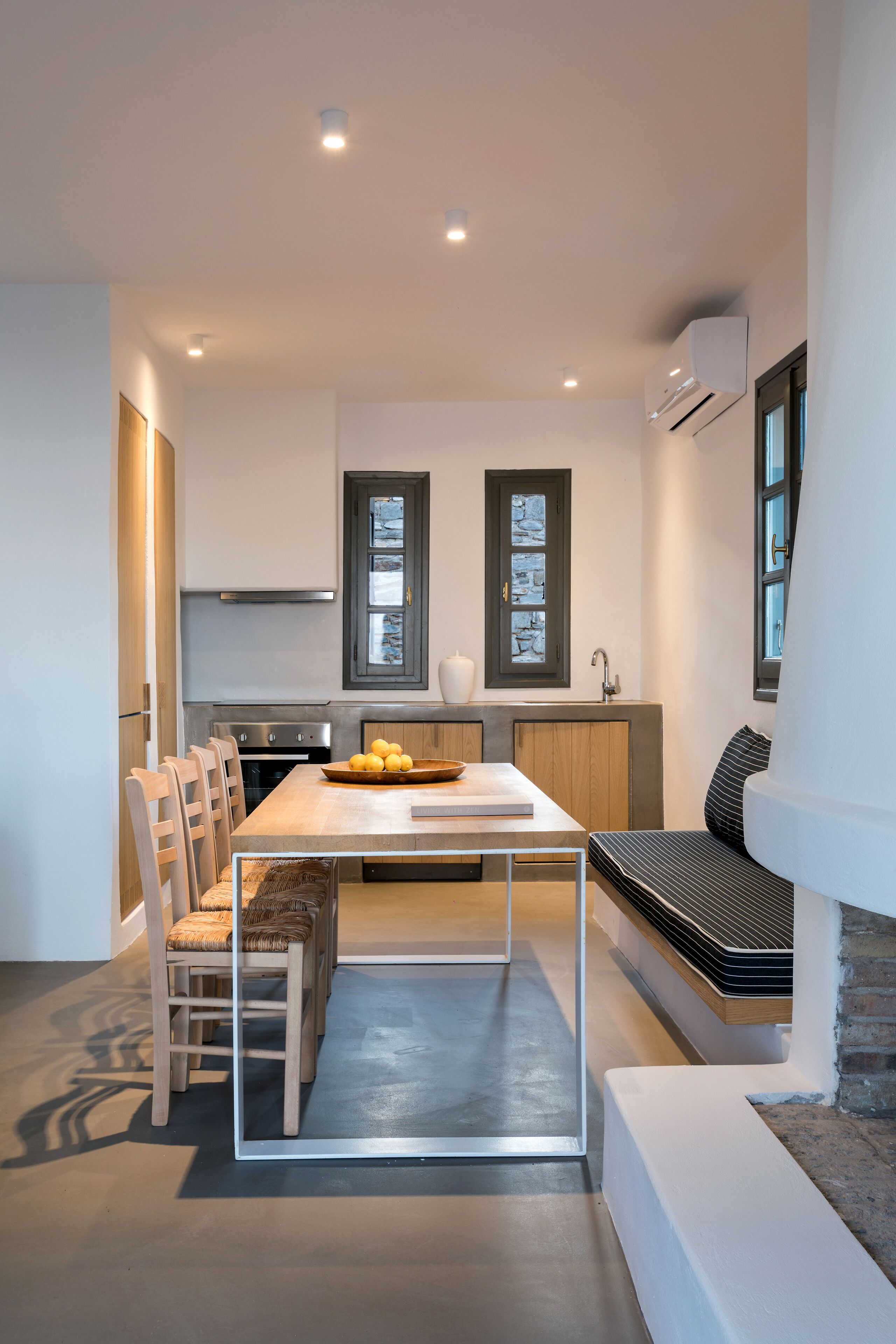 Une cuisine moderne avec un coin repas, des appareils électroménagers intégrés et un banc.