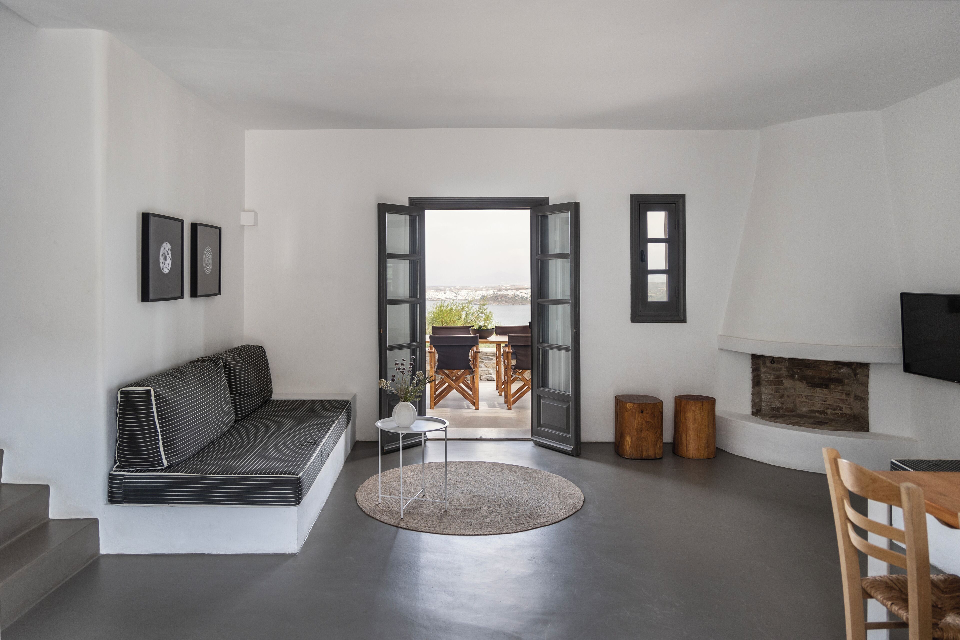 Ein modernes Wohnzimmer mit einer Couch, einem kleinen Tisch, einem Kamin und Blick durch eine offene Tür.