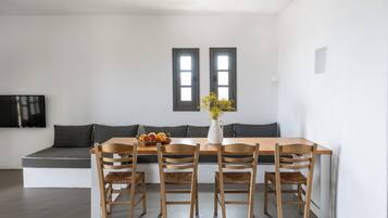 Eine moderne Küche mit einem Holztisch, vier Stühlen, einer Blumenvase und einem Fenster über der Spüle.