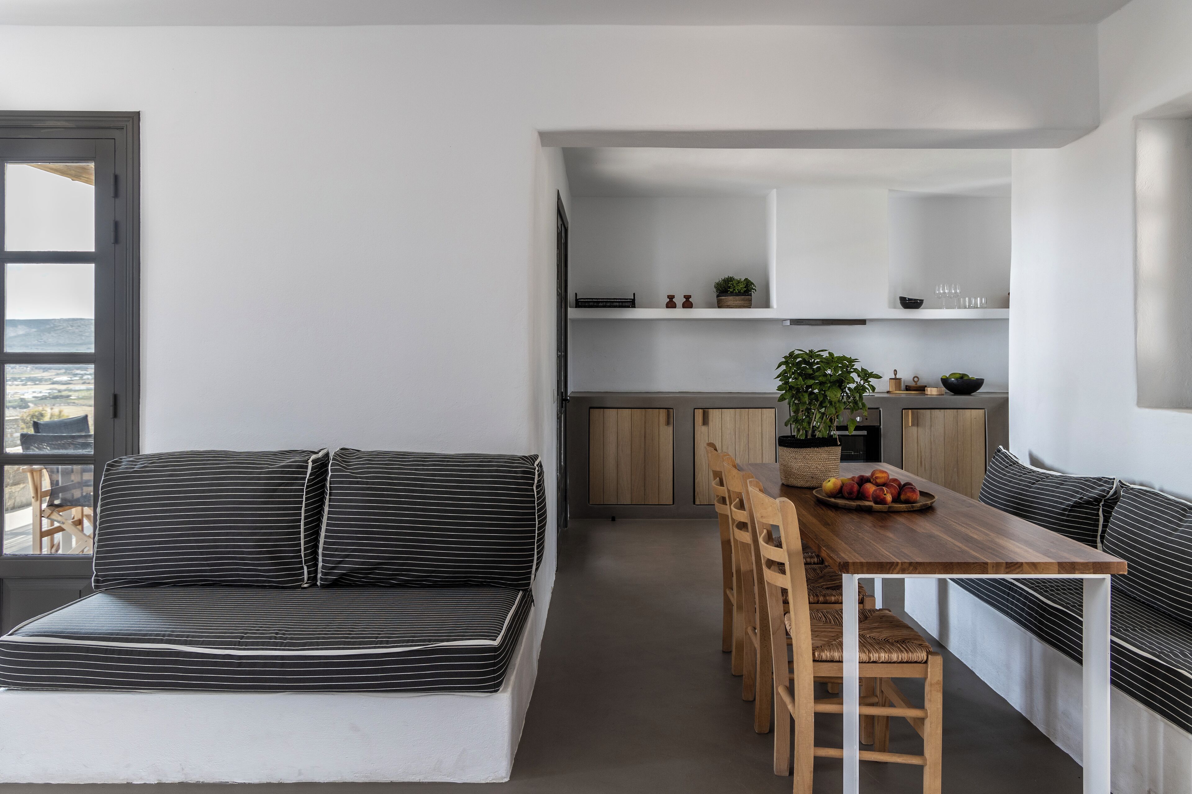 Un interior moderno con sofá, mesa de comedor, sillas y zona de cocina.