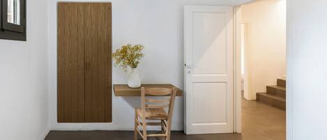 A room with a wooden panel wall, a white door, a small table with a vase of flowers, and a chair.