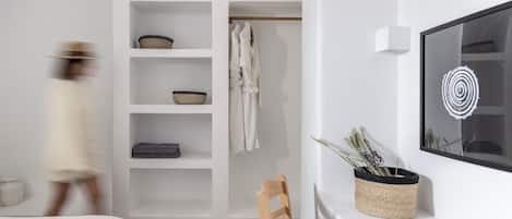 A modern bedroom with a bed, a wooden chair, a wardrobe with shelves, and a wall-mounted TV.