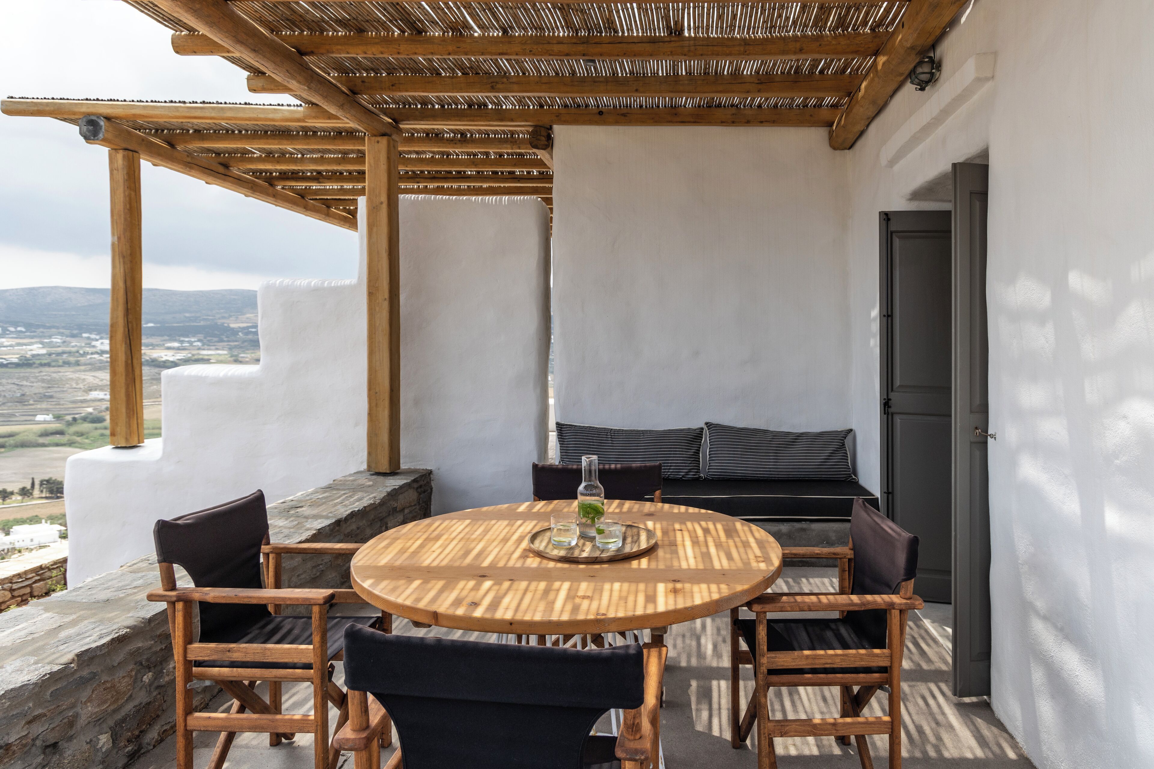 A wooden table and chairs set on a balcony with a view of the countryside.