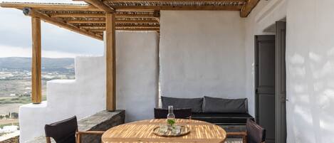 A wooden table and chairs set on a balcony with a view of the countryside.
