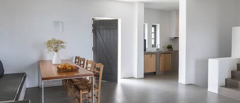 Un intérieur moderne comprenant un espace repas, une cuisine et un escalier.