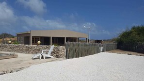A modern building with a flat roof, a covered patio area, and a gravel driveway. - Eco Resort Bonaire (Kralendijk)