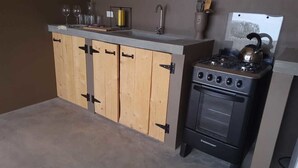 A compact kitchen with wooden cabinets, a gas stove, and a sink. - Eco Resort Bonaire (Kralendijk)