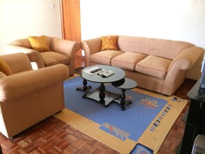 Relax in this inviting living room with a beige sofa set, round coffee table, and wooden parquet floor.