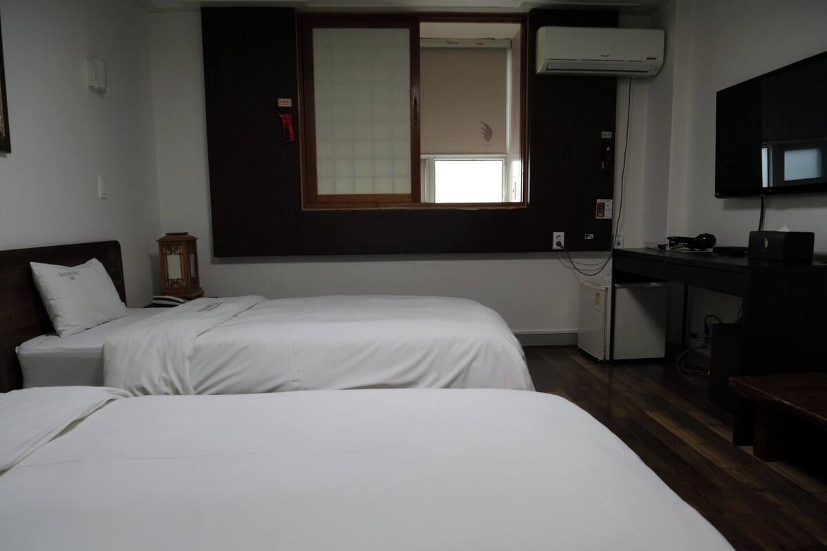 Une chambre d’hôtel avec deux lits, un bureau, une télévision et un appareil de climatisation.