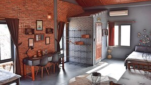 Una habitación con pared de ladrillo, un escritorio con una silla, una cama y un ventanal grande.
