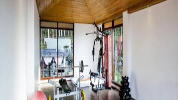 Ein Fitnessraum mit Holzboden, Trainingsgeräten und großen Fenstern.