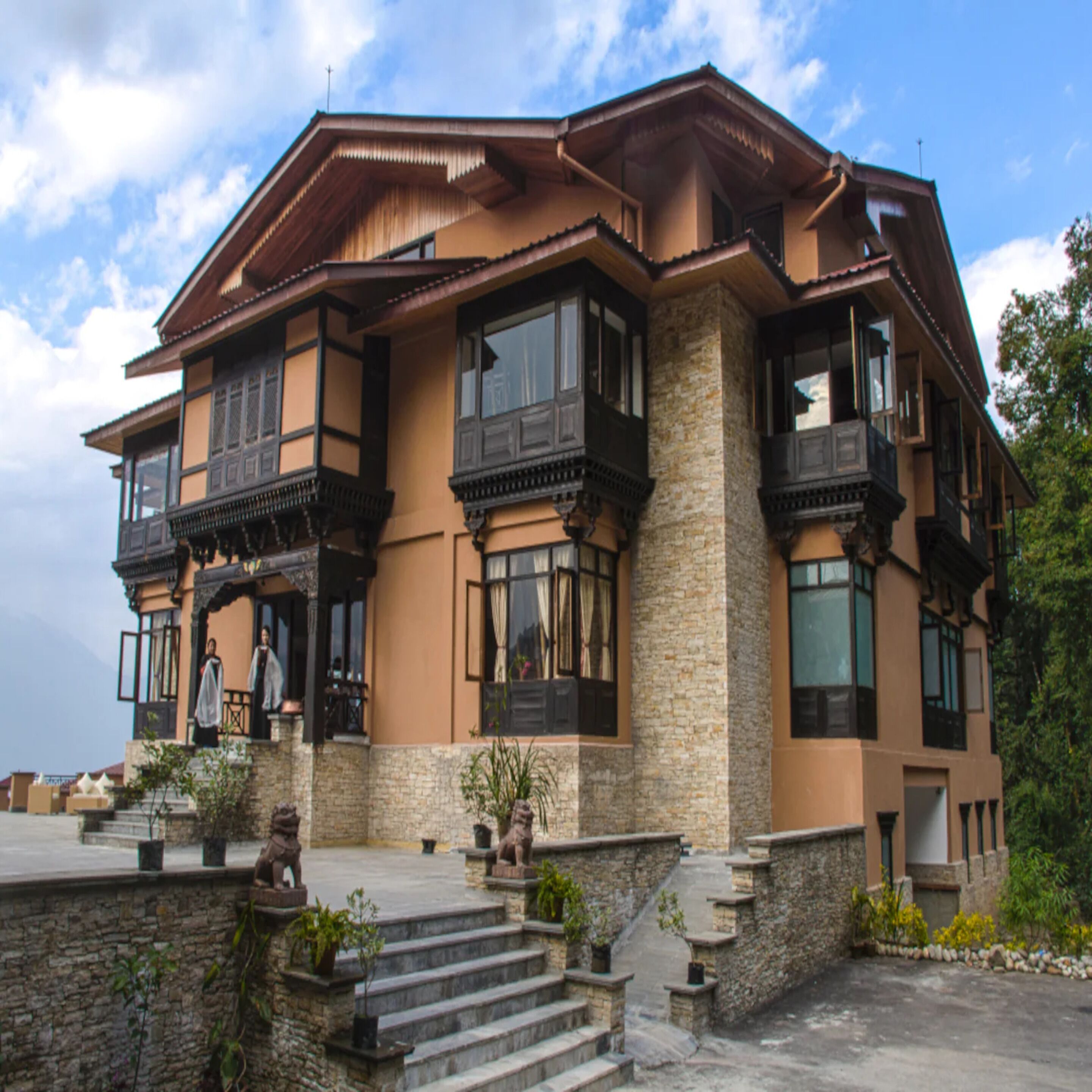Una casa de varios pisos con fachada de piedra, ventanas grandes y balcones.