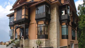 Una casa de varios pisos con fachada de piedra, ventanas grandes y balcones.