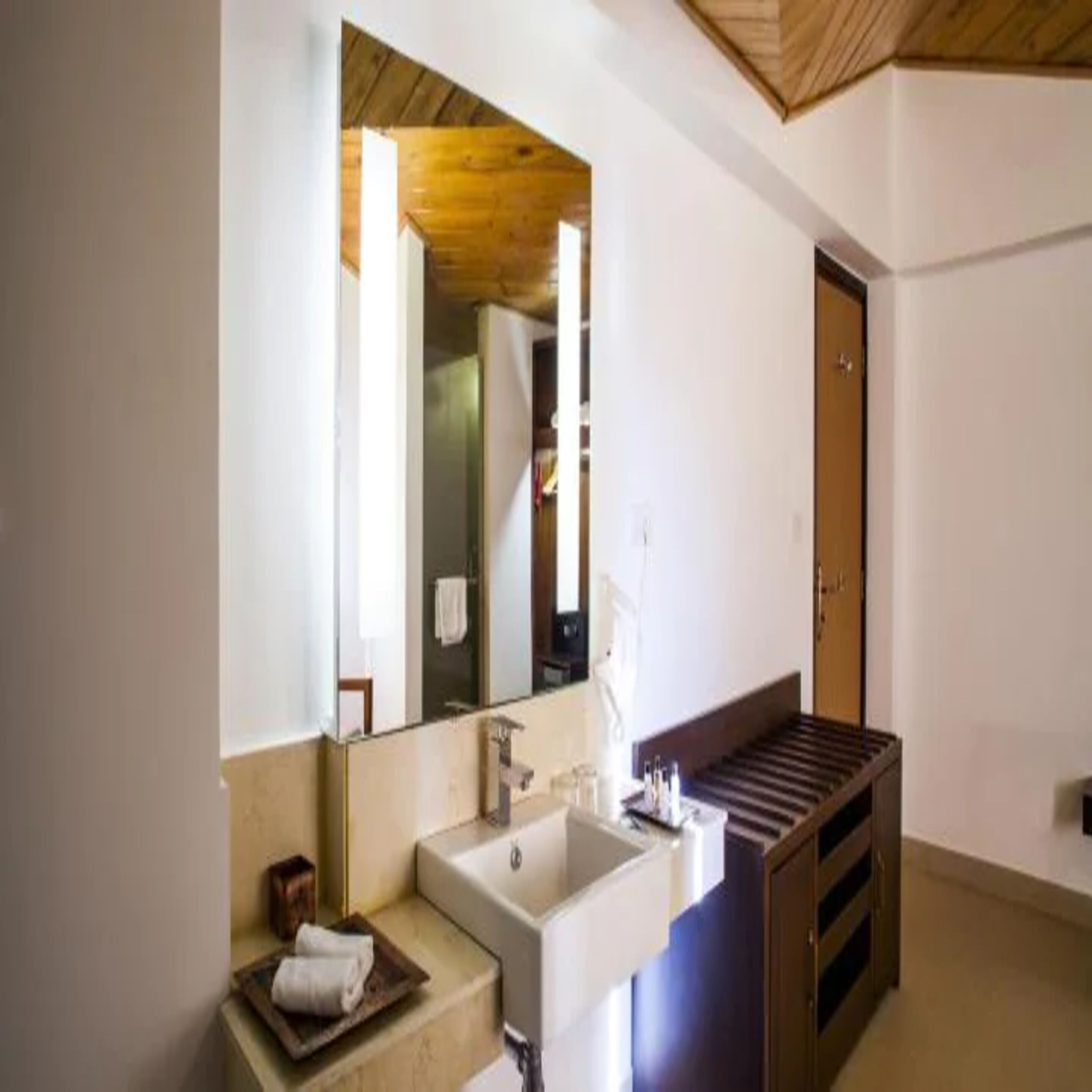 A modern bathroom with a large mirror, a wooden vanity, and a bathtub.