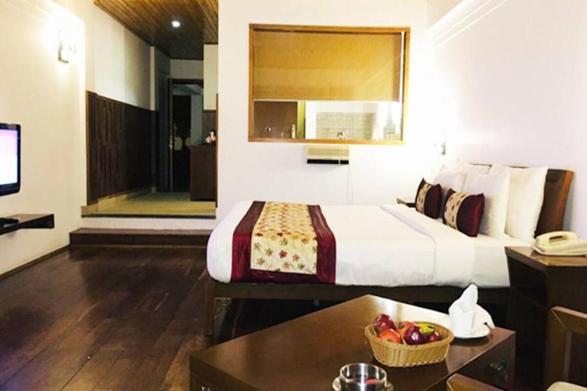 A hotel room with a bed, bedside table, and a small table with fruit.