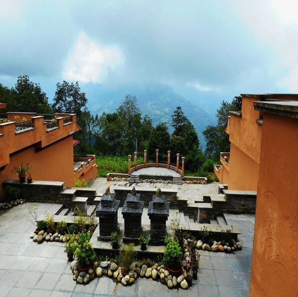 A courtyard with stone steps leading to a central area with a railing, surrounded by potted plants and trees. - The Chumbi Mountain Retreat (Gyalshing)