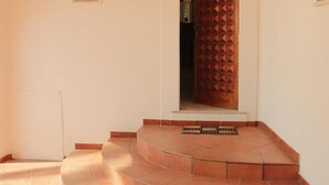 A set of terracotta steps leading to a wooden door with a geometric pattern. - Eremo di Montevergine : Calipso, cozy apartment with panoramic view (Forio)