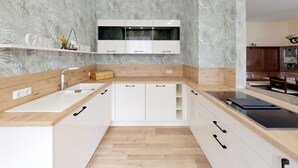 Eine moderne Küche mit weißen Schränken, einer Holz Arbeitsplatte und einem eingebauten Ofen.