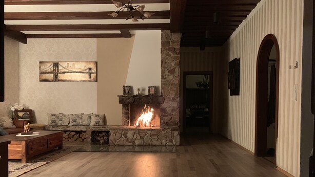 Ein Wohnzimmer mit Kamin aus Stein, Holzboden, einer Couch und einem Gemälde an der Wand.
