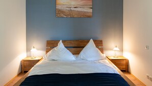 Ein Schlafzimmer mit einem hölzernen Bett, zwei Nachttischen mit Lampen, einem Gemälde an der Wand und einem Holzboden.