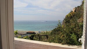 A balcony with a view of the sea and a distant ship.