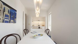 A narrow hallway with a white table, chairs, and a painting on the wall.