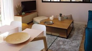 Moderni olohuone, jossa on ruokailutila, suuri peili ja näkymä keittiöön.