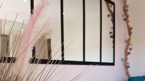 Moderni olohuone, jossa on suuri peili, puinen sohvapöytä ja ruukussa oleva viherkasvi.