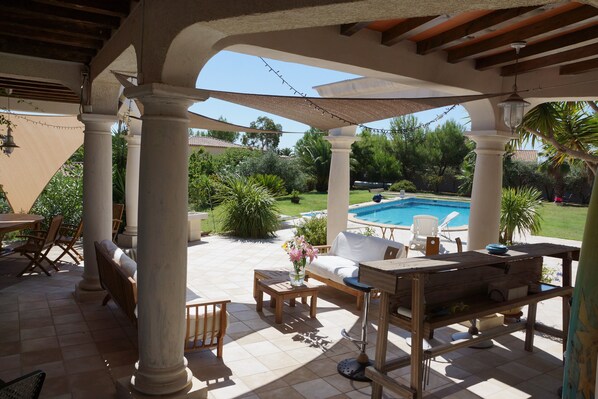 Relax in a serene outdoor space with a pool view, comfortable seating, and a charming table setting.