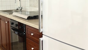 Eine Küche mit Spüle aus Edelstahl, Geschirrspüler und Kühlschrank in Weiß.