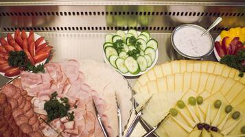 A buffet with various food items including sliced meats, cheeses, and vegetables.