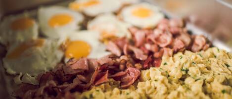 Un bufé con diversas opciones para el desayuno, como huevos, tocino y huevos revueltos.