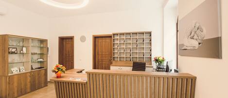 Un espace d’accueil comprenant un comptoir de réception en bois, une vitrine en verre, une porte en bois et une étagère fixée au mur.