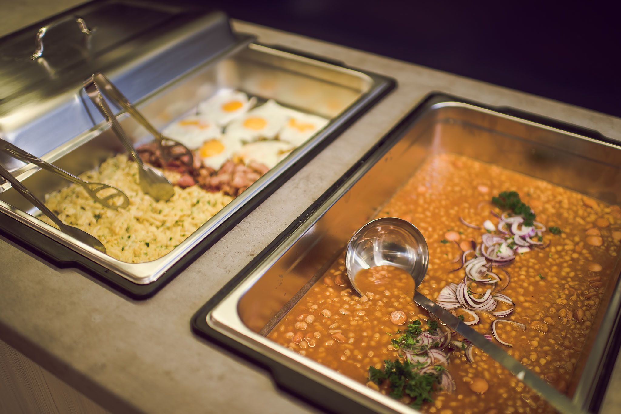 A buffet with various dishes including rice, beans, eggs, and meat.